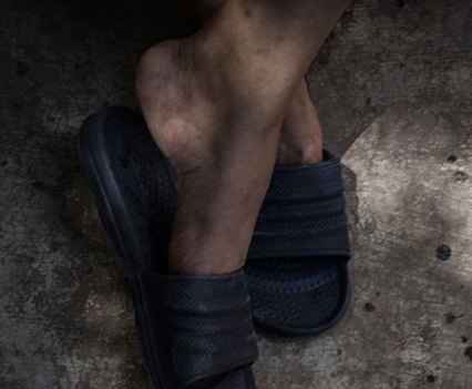 Feet in sandals crossed at the ankles