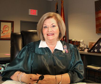 A judge sitting at a desk, smiling at the camera