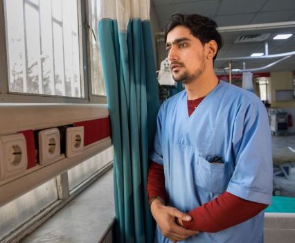 A medical professional looking pensively out of a window