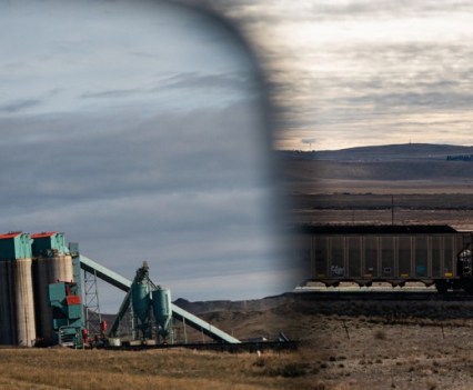 Part of the Eagle Butte operation is reflected in a car's side-view mirror as a train passes.