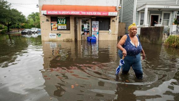 In downtown Charleston, Tonya O’Neal wades through floodwaters following a heavy rain to get back home after leaving Green’s Grocery on Bogard Street on June 13, 2021.