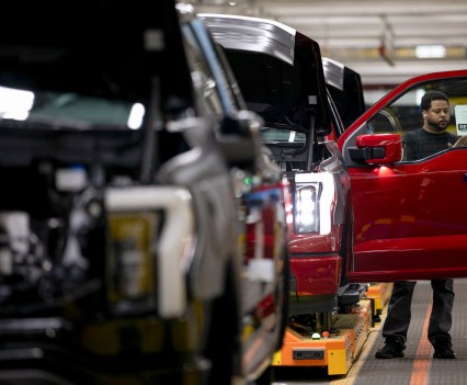 A worker adds a retail sticker to a newly assembled 2023 electric Ford F-150 Lightning