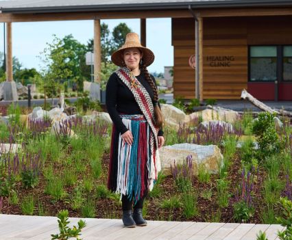 A woman in a colorful skirt stands on the sidewalk outside