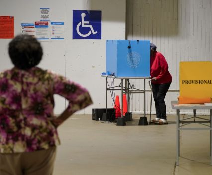 A prominent handicap sign displays over a privacy booth in a voting location