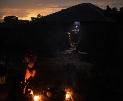 Residents cook as the sun sets over Meliandou. The village has no electricity, but some people have solar-powered lights