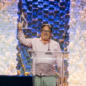 A man stands behind a podium holding up an Online Journalism Award trophy in victory